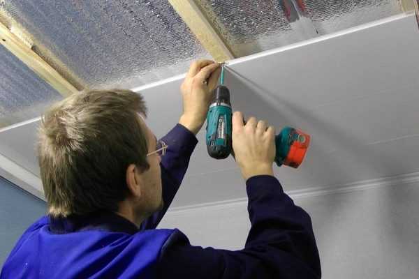 Мужчина облицовывает комнату ПВХ панелями Крепление ПВХ панелей